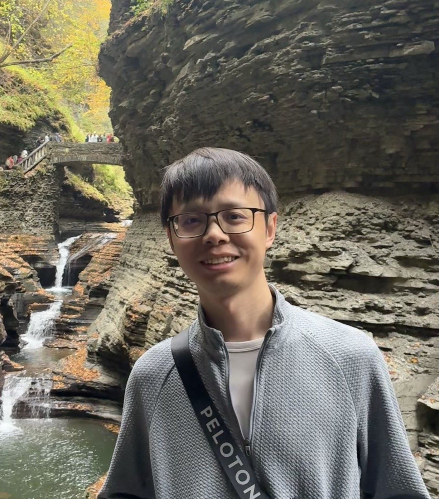Shi Qiu outdoors beside a waterfall and rocky gorge
